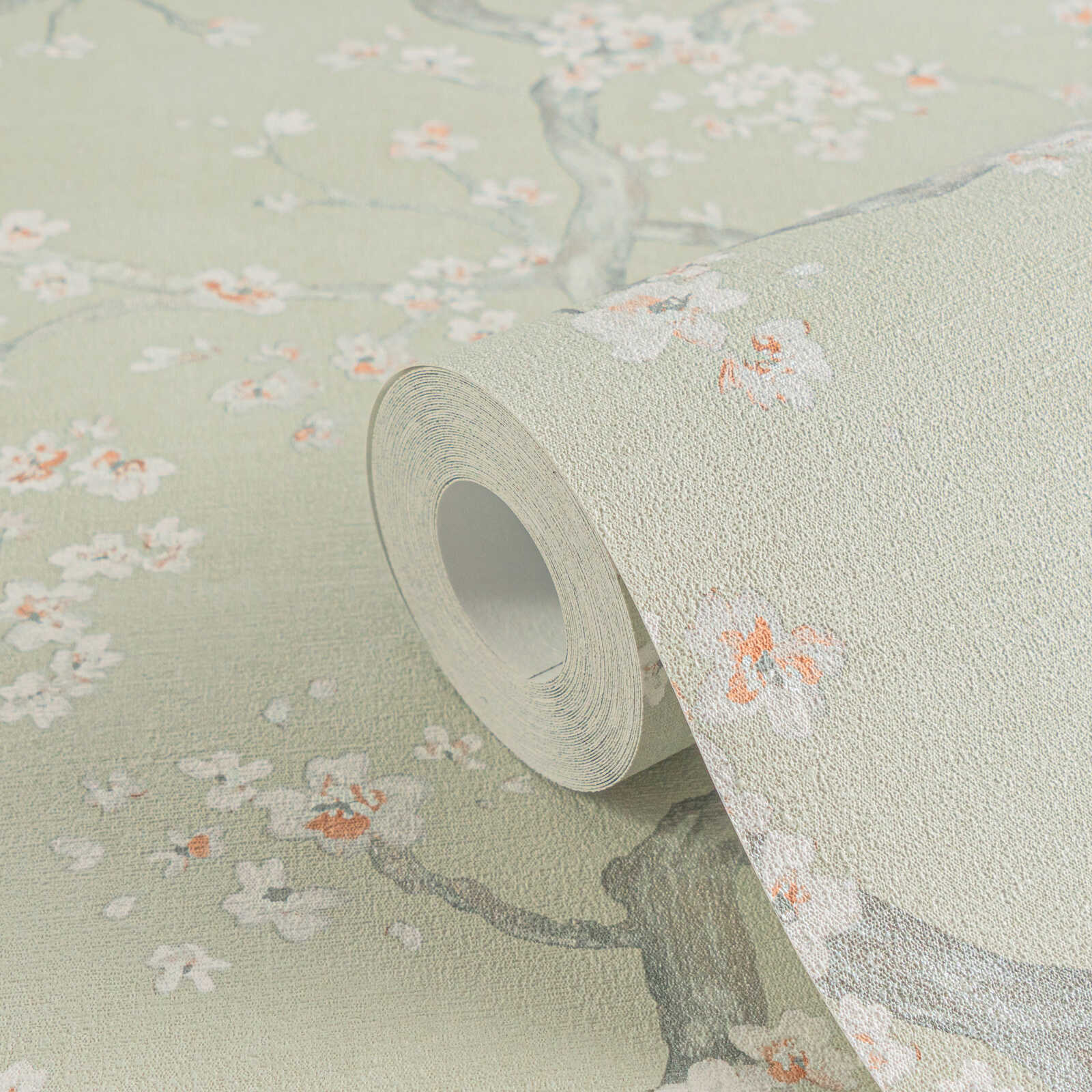 Zaļi pelēkas tapetes ar delikātu ķiršu ziedu rakstu un tekstūru - guļamistabas interjerā