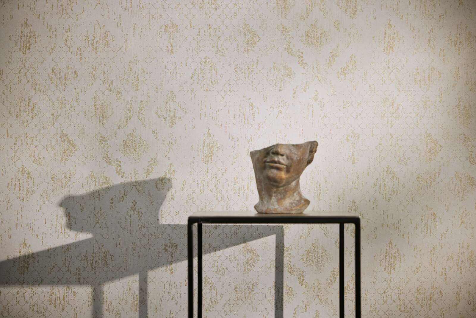 Ornamentālas tapetes ar zeltainiem akcentiem krēmkrāsas tonī - kombinācija ar mebelēm